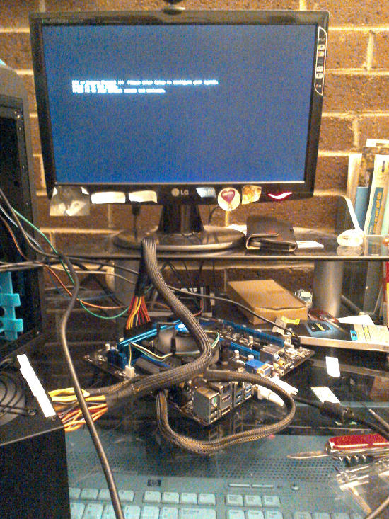 Cables from the power supply attached to the exposed motherboard with it being connected to the monitor.  Everything is working