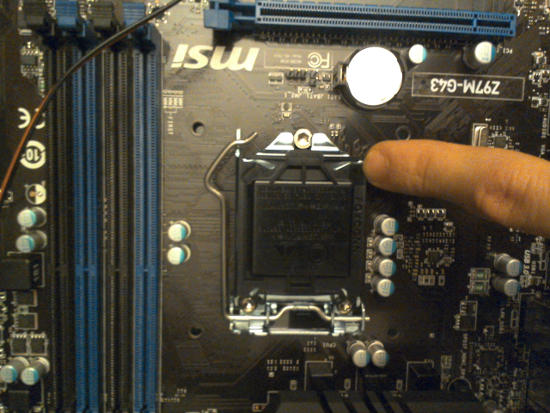 My finger on the motherboard's processor cover.